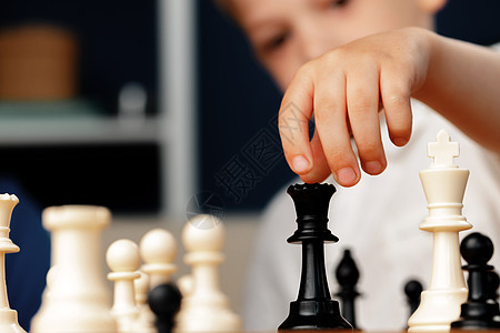 贴近一张照片 一个小男孩在下象棋微笑木板棋盘成人父母游戏教育儿子房间桌子图片