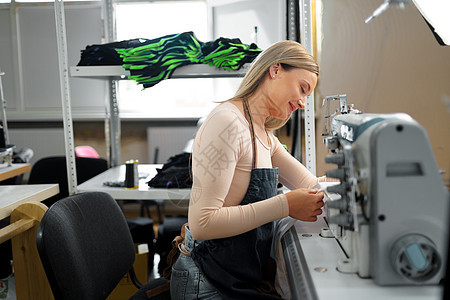 美丽的女性女裁缝在其工作场所从事织物加工工作职场微笑制造业工艺办公室女裁缝金发作坊缝纫衣服图片