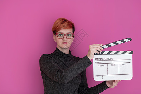 红发红发女人拿着粉红色背景的电影拍片运动记板黑板乐趣闲暇相机工作室行动导演视频图片