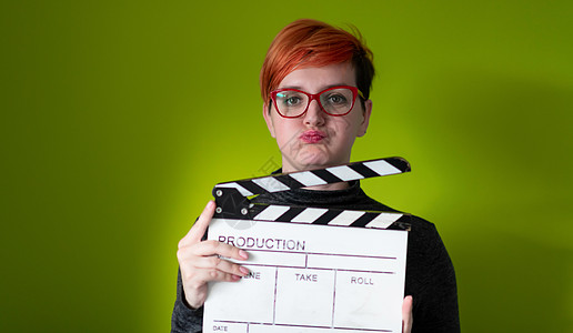 红发红发女人拿着绿背景的电影拍扣头发影响者运动摄影黑板微笑隔板记板生产闲暇图片