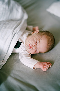 婴儿用拳头在床上睡觉图片