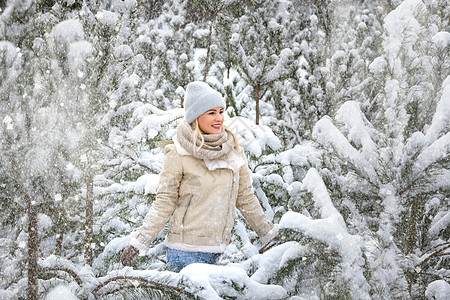 年轻的笑着快乐的白种女人和冬天森林里的松树枝 积极的情绪 走在多雪的天气微笑女士乐趣雪花帽子喜悦夹克假期松树快乐图片