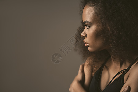 悲伤或与男友分手后 非洲裔美国女孩站在灰色背景中孤立的黑色上衣 人类情感 面部表情概念图片