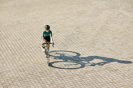 专业女自行车手穿着自行车服装和防护装备骑自行车 在温暖的阳光明媚的日子里在户外训练的鸟瞰图图片