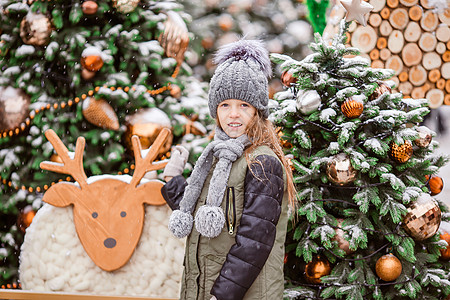 新的一年 在雪地的fir tree树枝附近的小快乐女孩礼物女儿地标女孩手套森林市场城市雪花帽子图片