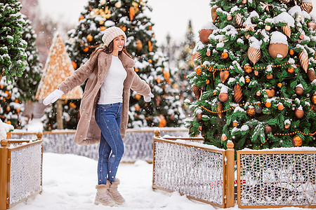 新的一年 在雪地的firtree树枝附近的快乐女孩喜悦微笑展示雪花季节市场手套礼物女士孩子图片