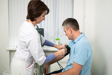 女医生在门诊办公室体检时用血压计给男病人测量血压 心脏病专家在心脏病医院检查男性患者的血压疾病全科诊所高血压诊断压力访问测试职业图片