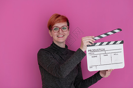 红发红发女人拿着粉红色背景的电影拍片闲暇隔板头发教育生产黑板导演记板影响者制片人图片