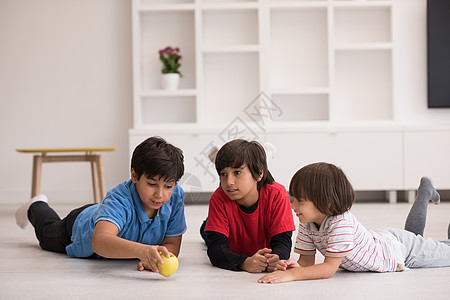 男孩在地板上拿着苹果玩得开心幼儿园手势说谎生活团体地面冒充木地板家庭男生图片