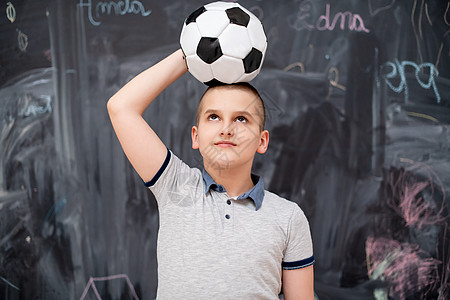 快乐的男孩在头上拿着足球球学校知识男性幼儿园学习课堂冒充微笑孩子小学生图片