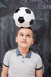 快乐的男孩在头上拿着足球球神童幼儿园运动员男性冒充孩子游戏知识瞳孔学习图片