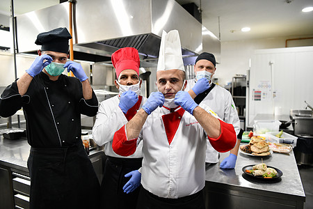 在冠状病毒新常态概念下 一群厨师戴着防护医用口罩和手套站在餐厅的厨房里保健食物面具疾病烹饪成人男性餐饮服务工作图片