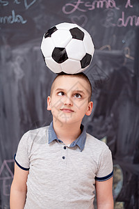快乐的男孩在头上拿着足球球幼儿园运动瞳孔神童微笑学习木板黑板粉笔童年图片