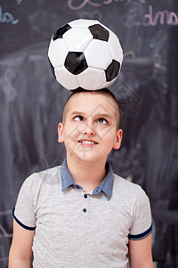 快乐的男孩在头上拿着足球球孩子游戏男生幼儿园小学生运动学习课堂黑板冒充图片