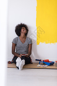 坐在地板上的后背女画家成人快乐房子滚筒微笑女性房间设计师女士公寓图片
