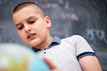 男孩在黑板前使用地球球学校男生粉笔瞳孔课堂幼儿园青少年木板孩子班级图片
