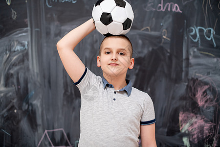 快乐的男孩在头上拿着足球球黑色孩子冒充知识瞳孔神童小学生男性学习男生图片