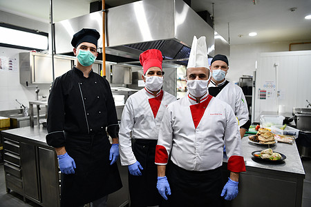 在冠状病毒新常态概念下 一群厨师戴着防护医用口罩和手套站在餐厅的厨房里卫生服务混血疾病美食商业面具成人安全餐饮图片