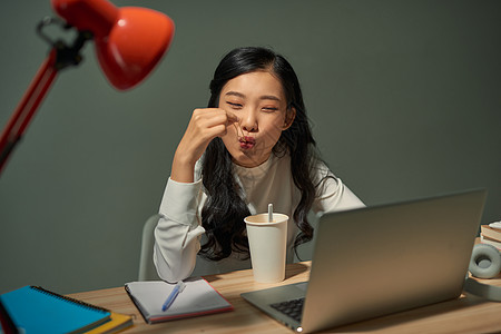 年轻女性在笔记本电脑上吃即时拉面 晚上深夜面条杯子拉面零食厨房垃圾女孩桌子晚餐女士图片