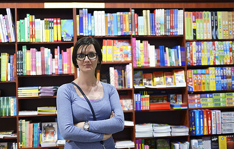 图书馆中的女性架子教育零售成人微笑学生大学学校店铺阅读图片