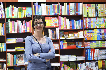 图书馆中的女性女孩学习书架教育店铺学校零售成人微笑学生图片