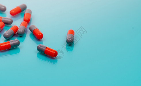 在蓝色背景的橙色和灰色胶囊药片 医药行业 处方药 医疗保健和医学 药房网页横幅 新药研发 健康科学背景图片