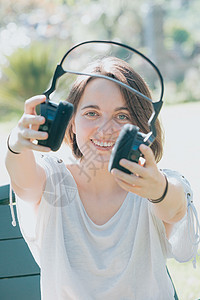 年轻女性在微笑 耳机 在外面听音乐 休闲概念 轻松的假期时 会在镜头前展示一个大耳机图片