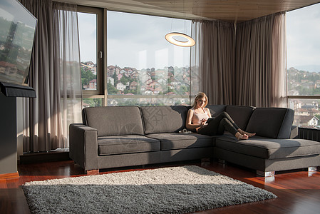 妇女在美丽的公寓使用平板药微笑闲暇电脑家庭生活客厅滚动药片长椅地毯沙发图片