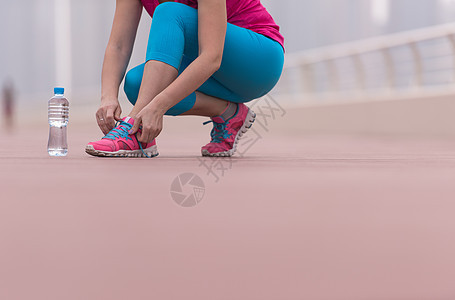 妇女在运动鞋上系鞋带衣服训练跑步运动员城市领带活力赛跑者女士慢跑者图片