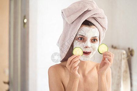 女孩照顾自己的美貌和健康皱纹美容治疗毛巾镜子擦洗保湿护理黄瓜鬼脸图片