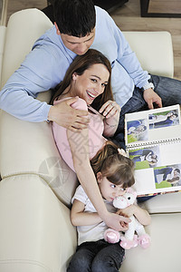 家庭幸福的家庭在家里看相片孩子沙发专辑妈妈成人爸爸母亲男人房子照片图片