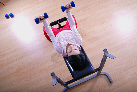 一名年轻女子在健身房举重女性腹肌活动闲暇哑铃俱乐部身体运动训练黑发图片