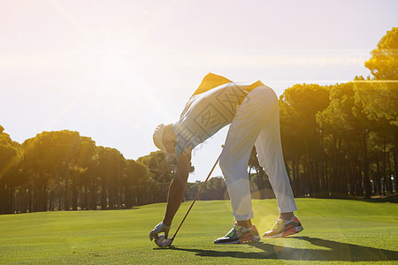 高尔夫球手把球打在Tee上帮助推杆夫球课程球座力量闲暇游戏男人草地背景图片