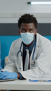 年轻专家用膝上型电脑坐在办公桌上的肖像男人卫生手套诊断药品外科办公室诊所保健职业图片