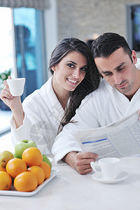 早餐时在厨房看报纸快乐的一对情侣男人女性杯子阅读家庭咖啡乐趣男性成人女士图片