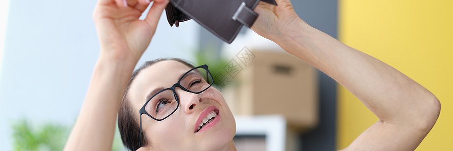 戴眼镜的年轻女青年在寻找空皮革钱包图片
