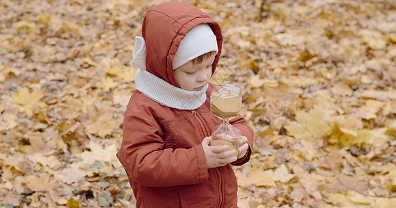 一个白人女孩在秋天的森林里 和玻璃沙漏一起玩耍图片