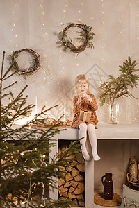 一个女孩在圣诞节前夕在一个为新年节日装饰的美丽房子里玩耍 斯堪的纳维亚式的内地有活林树和木质楼梯圣诞礼物孩子礼物女孩工艺硬木客厅图片