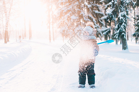 在冬季生活方式中 男孩用铲子扔雪 冬天散步 一篇关于儿童冬季闲暇的文章 文告季节雪堆孩子乐趣幸福童年投掷帽子公园孩子们图片