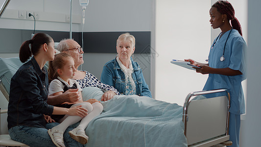 家庭探视在医院病房和护士谈话的退休男子;图片