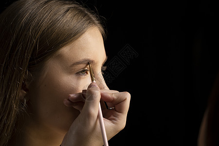 化妆师在美丽的女人脸上画眉毛 化妆师的手正在画年轻美女模特的眉毛 化妆过程中头发皮肤睫毛女性黑发粉末职业时尚女孩女士图片