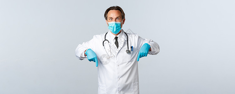 Covid19 预防病毒 医护人员和疫苗接种概念 戴着医用口罩和丁香的男医生震惊地喘着粗气 对冠状病毒的爆发百分比做出反应 指指图片