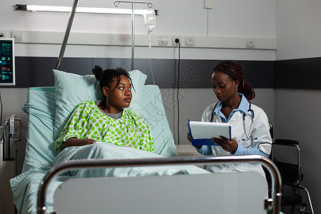 坐在生病的病人旁边的非洲裔美国医生医生询问医疗问题图片