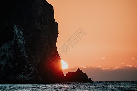 海上的红色燃烧日落与岩石火山悬崖 抽象自然夏季或春季海洋背景 金色温暖水面上的小波浪与来自太阳的散景灯海滩运动晴天天空火花温泉阳图片