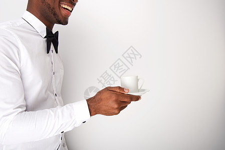 快乐的非洲美国服务器用白墙端着咖啡杯图片