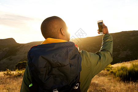 在山上用手机自拍的非洲男子徒步远足后方图片