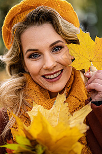 特写 穿着米色针织贝雷帽的年轻女子手拿秋叶 秋天黄色的花园或公园 秋叶的美丽的微笑的少妇闲暇头发眼睛女孩快乐森林树叶季节喜悦女性图片