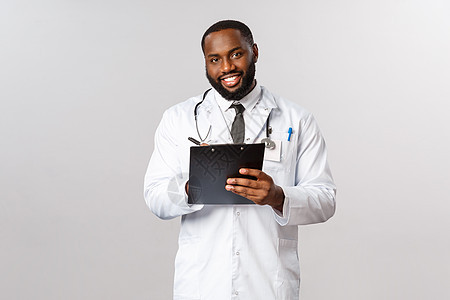 医学 covid19 治疗和医院理念 英俊的非洲裔美国医生治疗病人 倾听人的疾病或症状 在检查期间写下剪贴板保健卫生治疗师感染疫图片