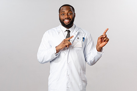 友善的英俊英俊的非洲美国男医生解释主要症状covid19 显示图表或处方说明如何安全 指向右上角和微笑 建议使用面罩卫生疾病保健图片
