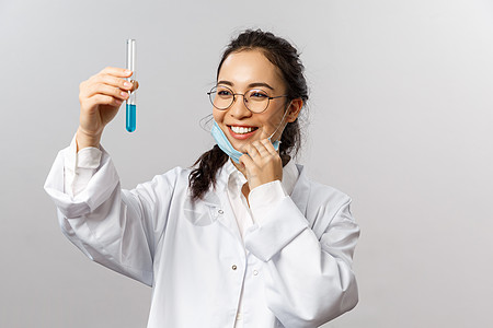 医生 感染者 研究和 covid19 概念 松了一口气 高兴的亚洲女孩摘下医用口罩 满意地微笑着看着装着疫苗 发明疗法或新药的小图片